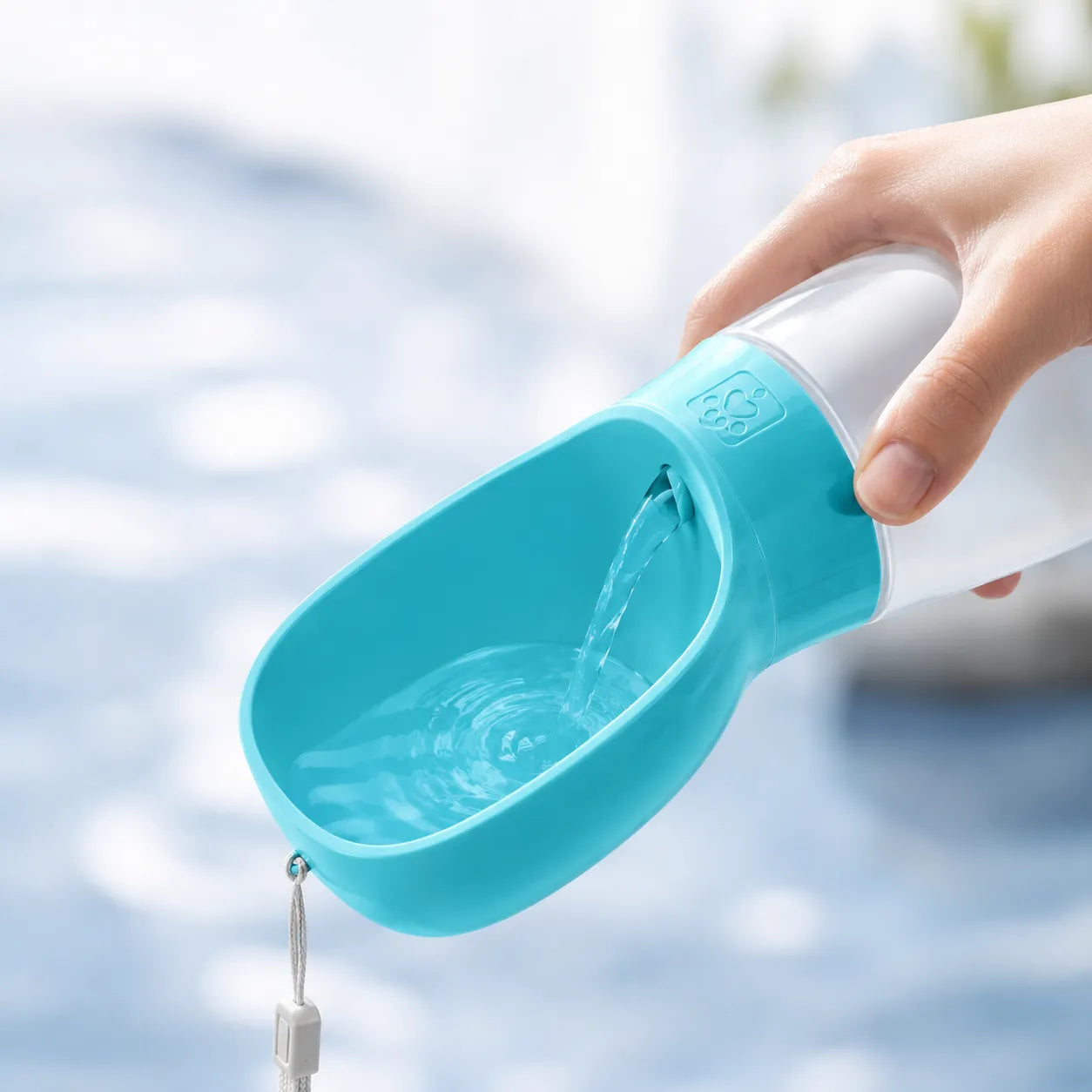 Blue pet water bottle with a hand holding it against a blurred outdoor background